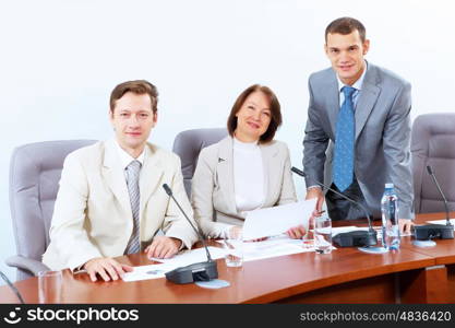 Three businesspeople at meeting. Image of three businesspeople sitting at table at conference