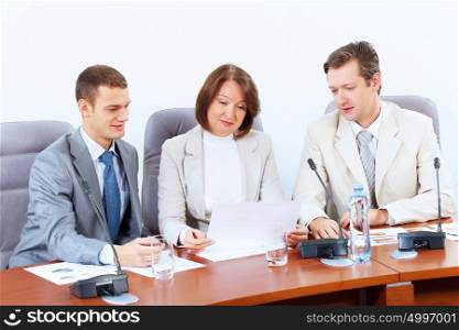 Three businesspeople at meeting. Image of three businesspeople sitting at table at conference