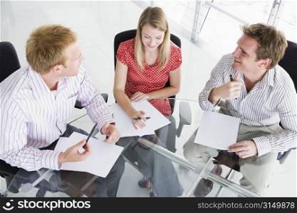 Three businesspeople in a boardroom looking at paperwork