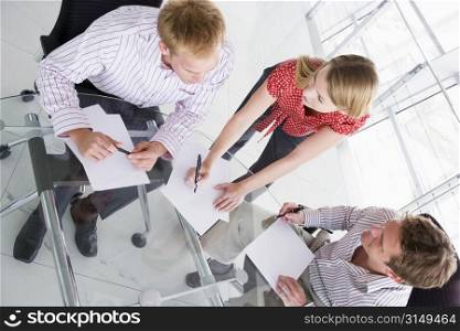 Three businesspeople in boardroom with paperwork