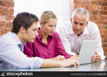 Three businesspeople in office looking at laptop