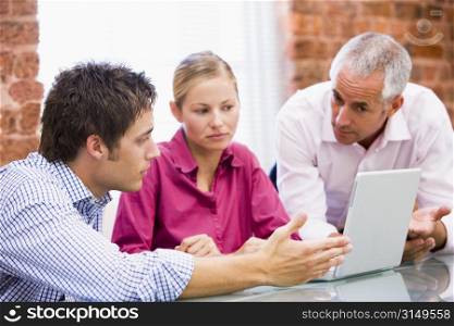 Three businesspeople in office with laptop