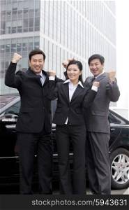 Three businesspeople outdoors cheering