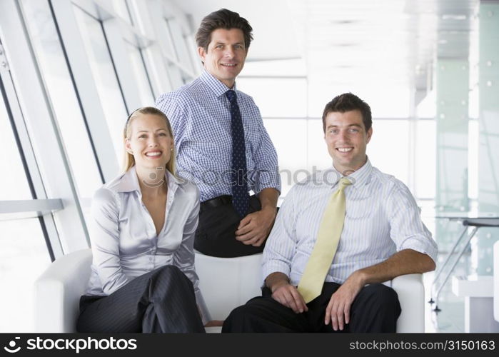 Three businesspeople sitting in office lobby smiling