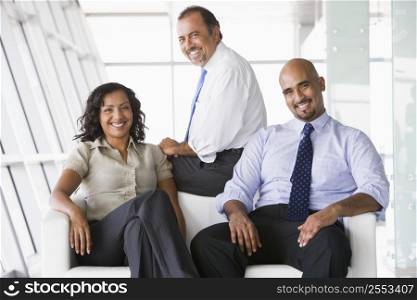Three businesspeople sitting indoors smiling (high key/selective focus)