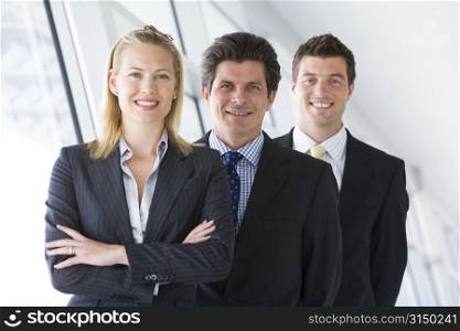 Three businesspeople standing in corridor smiling