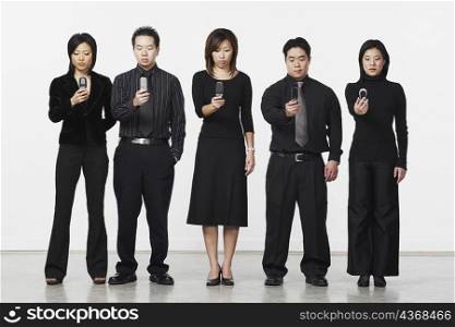 Three businesswomen and two businessmen holding mobile phones