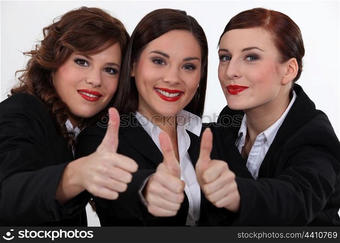 Three businesswomen giving the thumbs-up