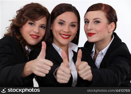 Three businesswomen giving the thumbs-up