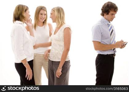 Three businesswomen gossiping and a businessman using a personal data assistant