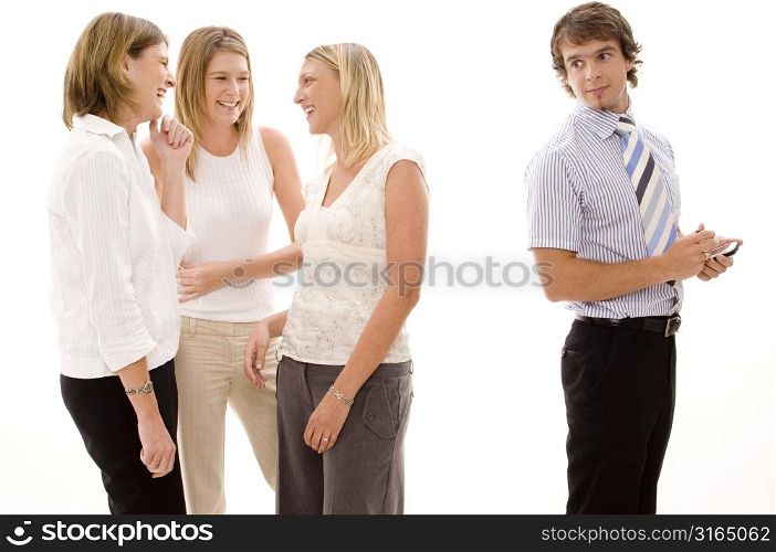 Three businesswomen gossiping behind a businessman
