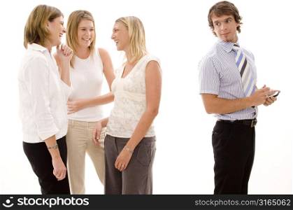 Three businesswomen gossiping behind a businessman