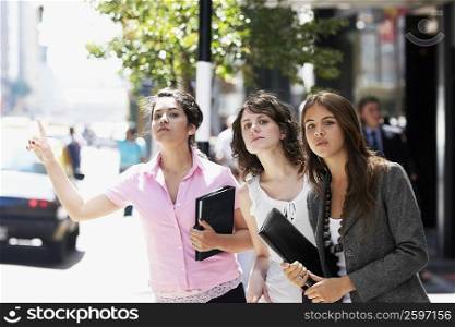 Three businesswomen hailing a taxi at the roadside