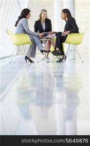 Three Businesswomen Meeting Around Table In Modern Office