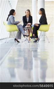 Three Businesswomen Meeting Around Table In Modern Office