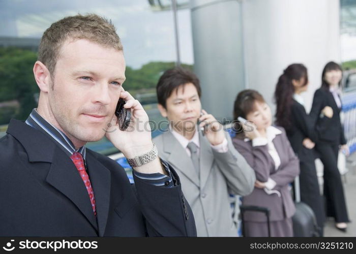 Three businesswomen with two businessmen waiting at an airport lounge