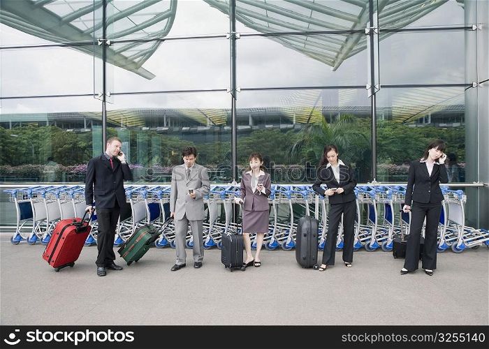 Three businesswomen with two businessmen waiting at an airport lounge