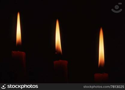Three candles in dark background