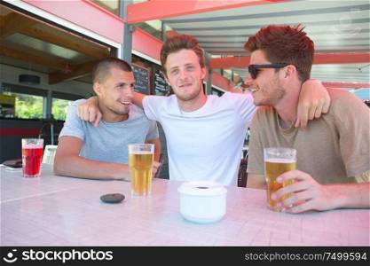 three casual joyful friends laughing and refreshing at bar terrace