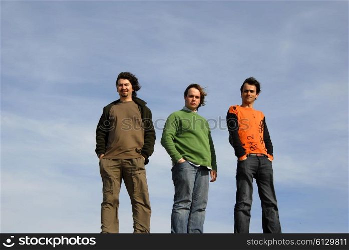 three casual young men with the sky as background