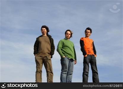 three casual young men with the sky as background