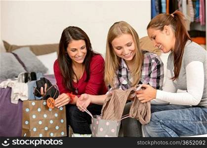 Three cheerful girls with clothes from sale shopping bags