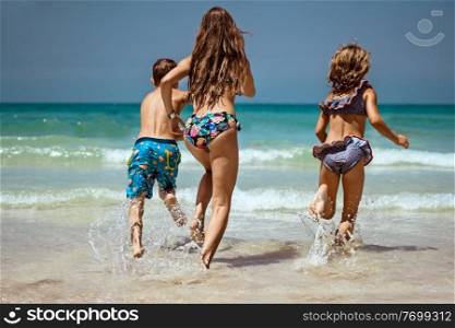 Three Cheerful Kids Running on the Beach. Happy Family With Pleasure Playing Game Together Outdoors. Enjoying Summer Holidays on the Beach Resort.. Happy Kids on the Beach