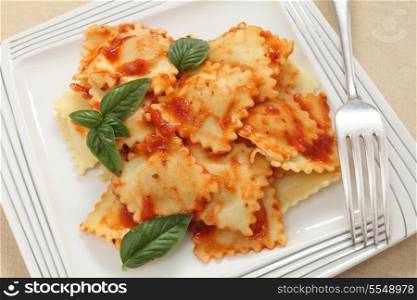 Three cheese ravioli in a pasta sauce with herbs close-up