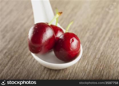 Three cherries laying on a white spoon