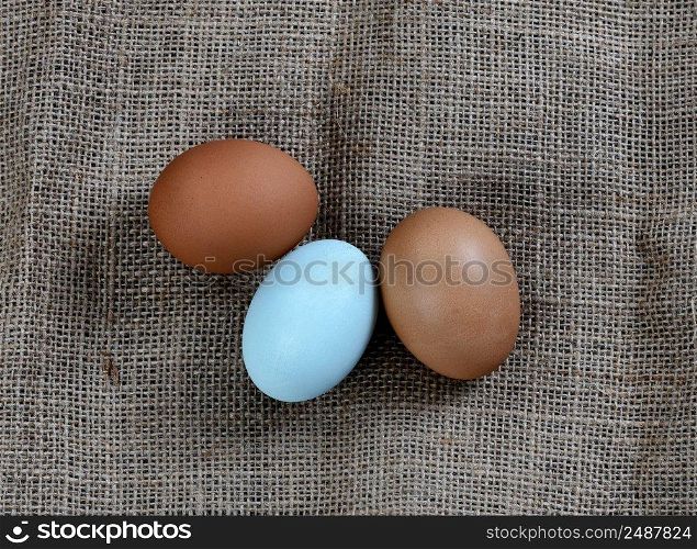 Three chicken eggs lying on burlap setting in close up view 