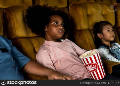 Three children having fun and enjoy watching movie in cinema