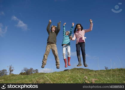 Three children jumping on hill