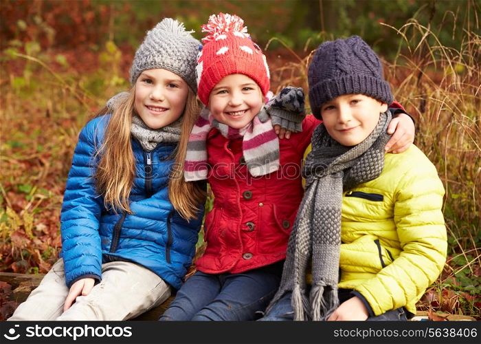 Three Children On Walk Through Winter Woodland
