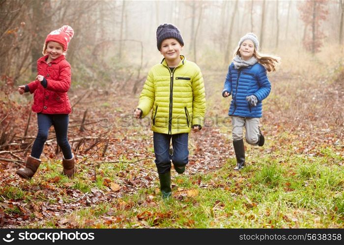 Three Children Running Through Winter Woodland