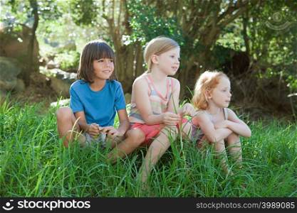 Three children sitting on grass