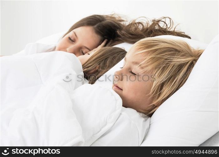 Three children sleeping in bed. Three beautiful children sleeping in bed under one white blanket