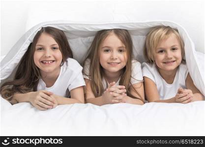 Three children under blanket. Three happy smiling children under blanket at home