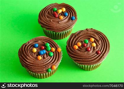 Three chocolate cupcakes isolated on a green background