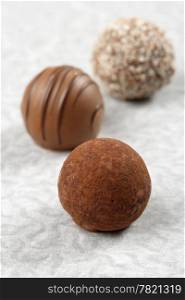 Three chocolate truffles on textured paper. Very Shallow depth of field, focusing on first truffle.