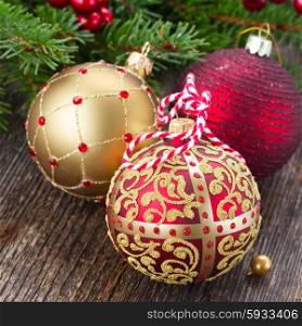 three christmas balls with fir tree on wooden background. red and golden christmas balls