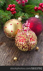 three christmas balls with fir tree on wooden background. red and golden christmas balls