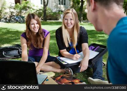 Three classmates studying together outdoors
