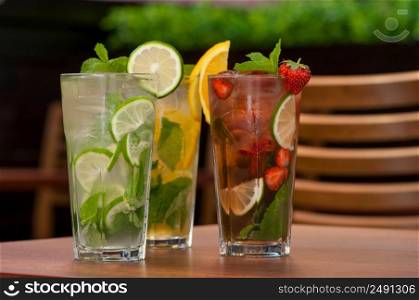 three cold drinks with citrus and strawberries in a glass on the table. cold drink with citrus on the table