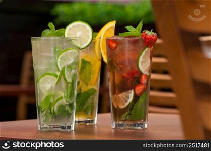 three cold drinks with citrus and strawberries in a glass on the table. cold drink with citrus on the table