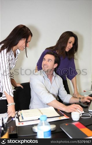 Three colleagues gathered around desk