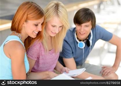 Three college friends studying together looking into book summer time
