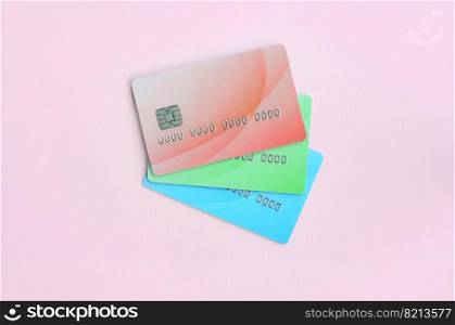 Three colored credit cards lay on a pastel pink background. The concept of a variety of banking services and types of bank card applications. Concept of variety of banking services and bank card applications
