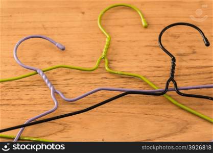 three colored hangers on a wooden table