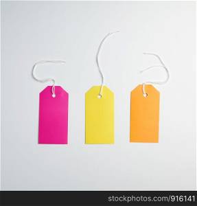 three colored paper tags on a white rope, white background
