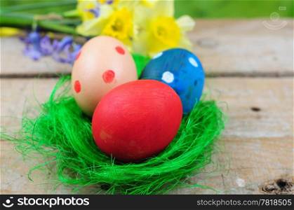 Three colorful easter eggs in green grass nest